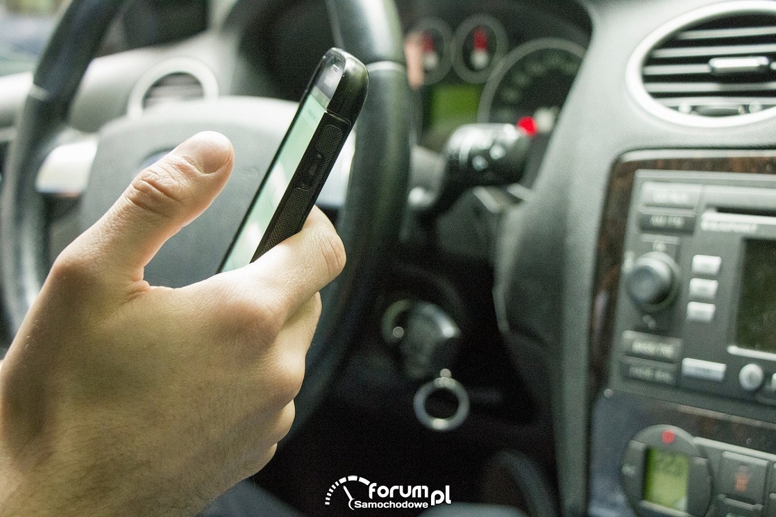 Telefon trzymany w ręku podczas jazdy samochodowem